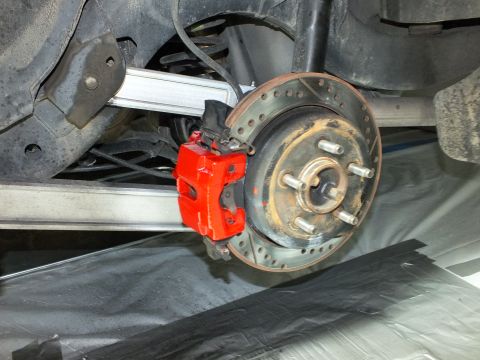 2003 Ford Crown Victoria - Rear suspension view showing red caliper, drilled rotor and a polished aluminum control arm.