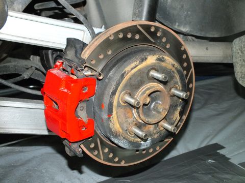 2003 Ford Crown Victoria - Rear brake assembly with red caliper and drilled rotor mounted on a five-stud hub.