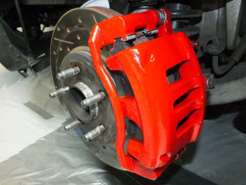 2003 Ford Crown Victoria - Detail of a red caliper and brake pads over a drilled rotor on a five-stud front hub.