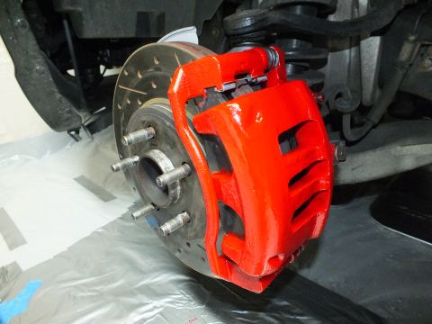 2003 Ford Crown Victoria - Front red caliper showing brake pads clamped over a cross-drilled rotor on a five-stud hub.