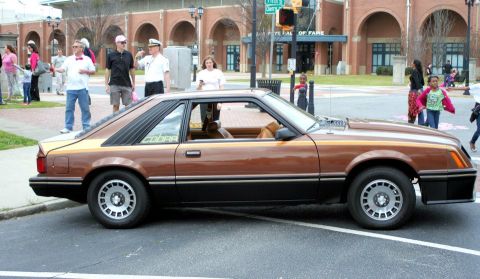 1980 Ford Mustang - This 1980 Ford Mustang Cobra is parked on a street with people in the background.