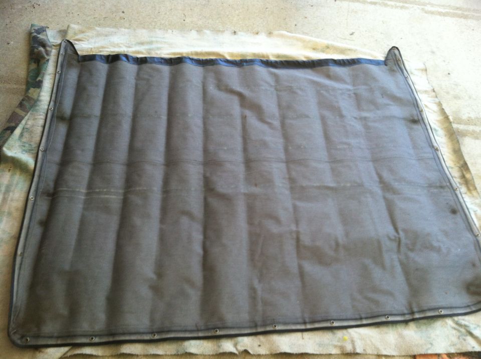 Gray padded canvas top with black trim and metal grommets, laid flat on a cloth