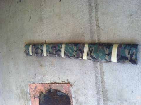 1990 Ford Bronco - A rolled up piece of camouflage fabric secured with white tape lies on a concrete surface.