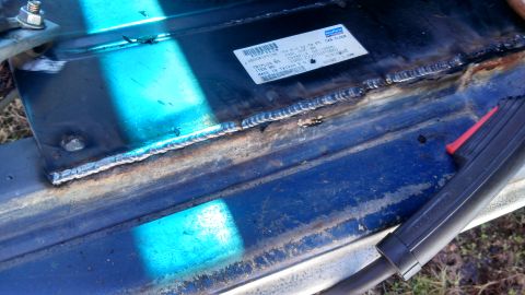 1979 Ford Bronco - A close-up view of a metal panel that has been welded, with a label attached.
