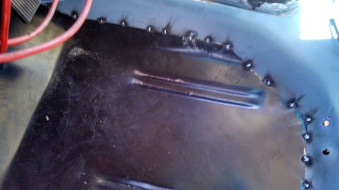 1979 Ford Bronco - Close-up of a welded metal floor pan, showing repair work and a red wire.