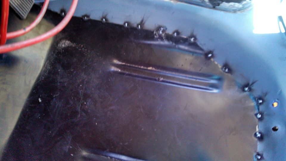 Welded metal floor pan with red wire and pedal visible