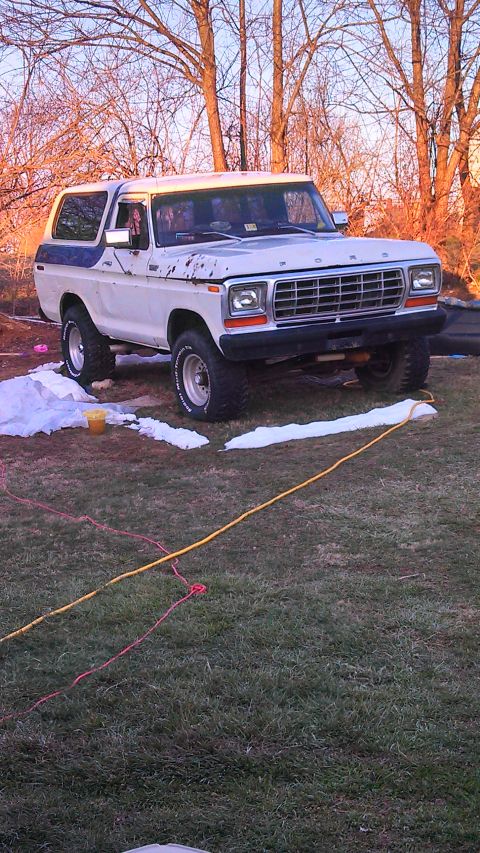 1979 Ford Bronco - A white and blue Ford Bronco sits on a grassy lawn with trees in the background.