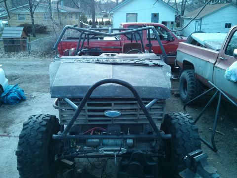 1986 Ford Bronco - This heavily modified vehicle features a prominent roll cage and winch, with other trucks visible in the background.
