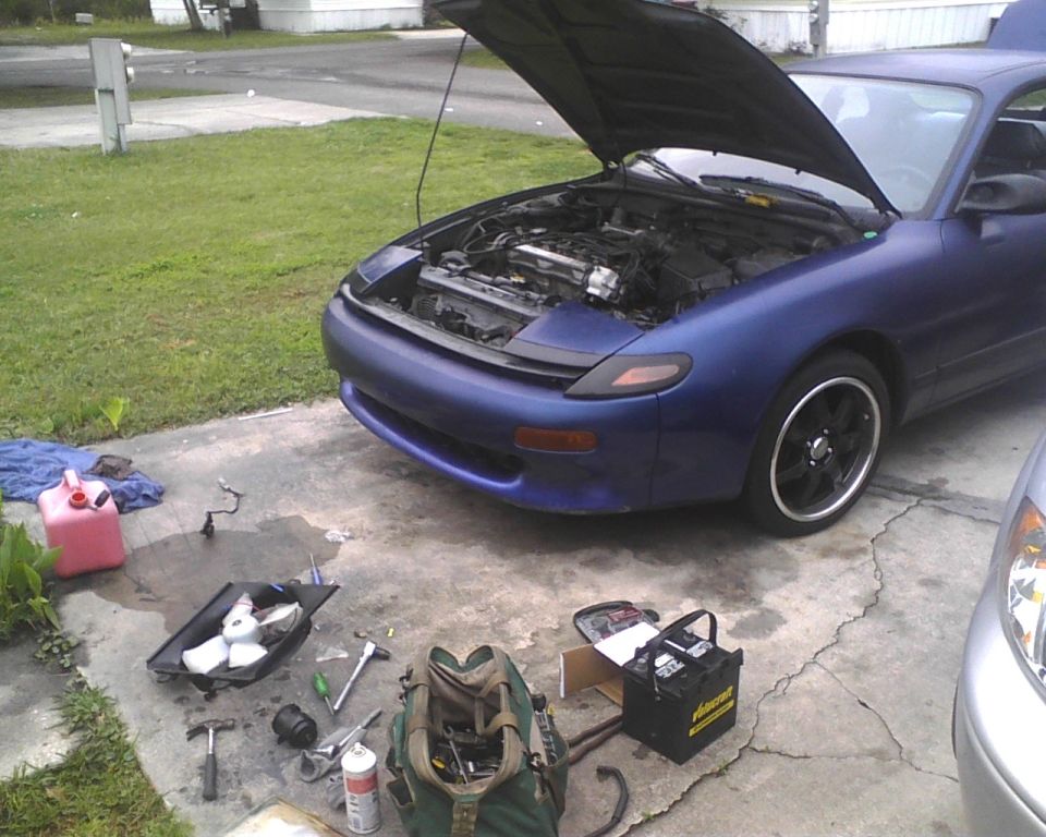 Blue 1991 Toyota Celica with hood open, tools and battery on driveway