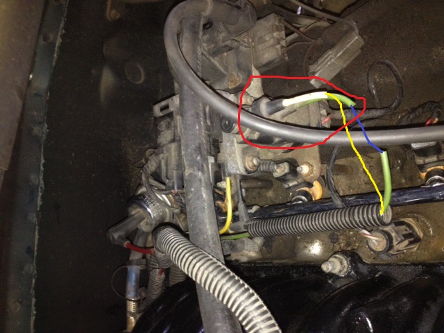 Close-up of engine wiring with a red circle around a connector and colored wires