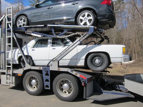 1991 Ford LTD Crown Victoria - A white 1991 Ford Crown Victoria LTD is transported on the lower deck of a car carrier.
