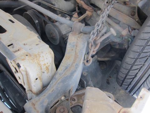 1991 Ford LTD Crown Victoria - Close-up view of engine bay components, showing rust and a hanging chain.