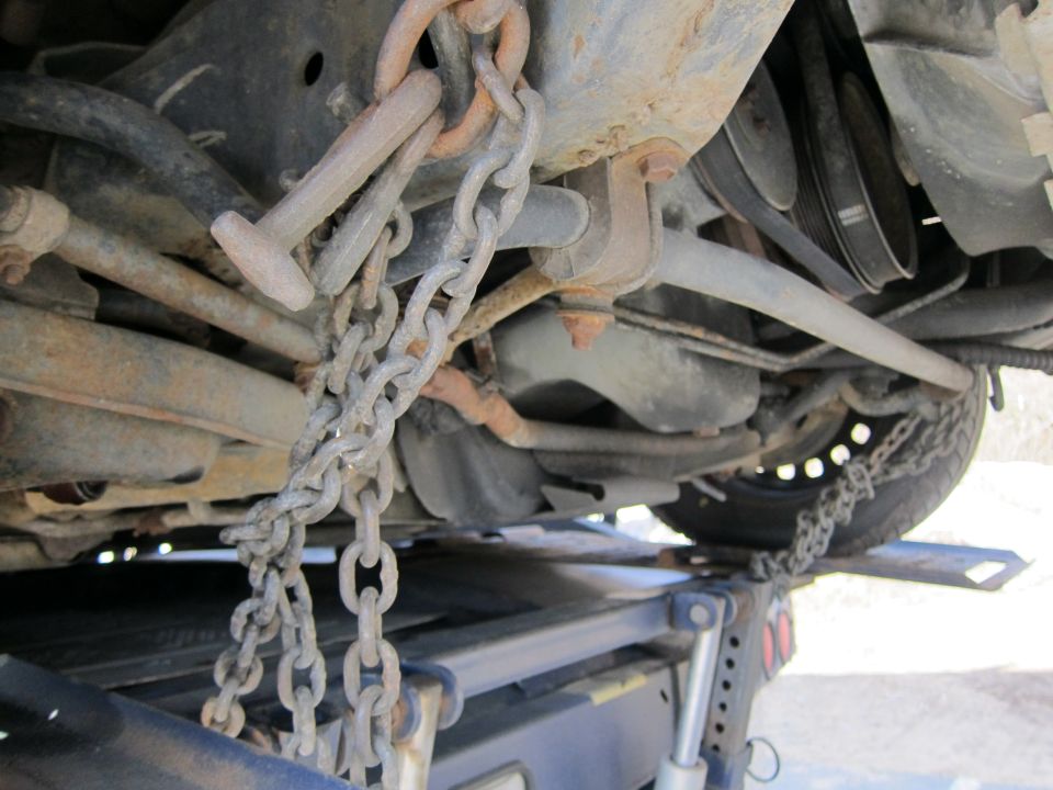 Chains securing the undercarriage of a vehicle onto a tow truck