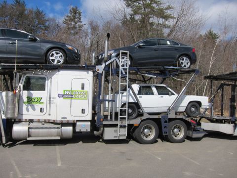1991 Ford LTD Crown Victoria - A car carrier truck is loaded with multiple vehicles, showing a side view of the transport.