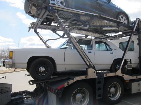 1991 Ford LTD Crown Victoria - White 1991 Ford Crown Victoria LTD being transported on a car carrier with another vehicle above.