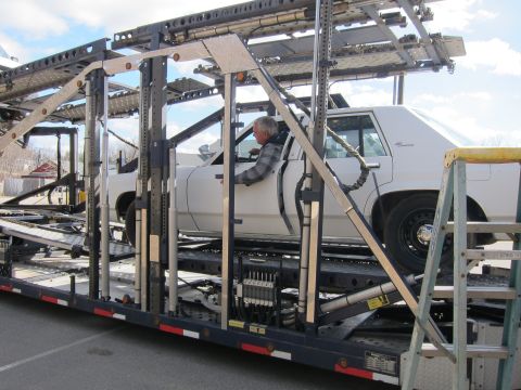 1991 Ford LTD Crown Victoria - A white 1991 Ford Crown Victoria LTD is loaded onto a car carrier, with a man visible in the driver's seat.
