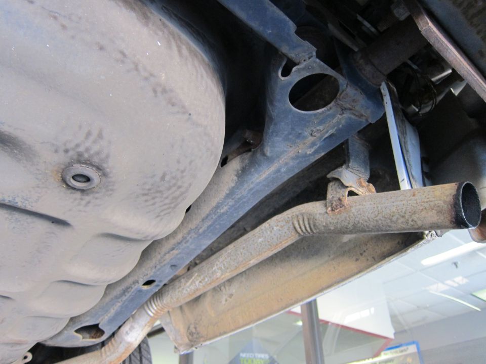 Underside view of a car's exhaust pipe and fuel tank