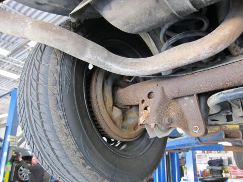 1991 Ford LTD Crown Victoria - Close-up of a vehicle's rear axle and suspension system, with a tire and brake drum visible.