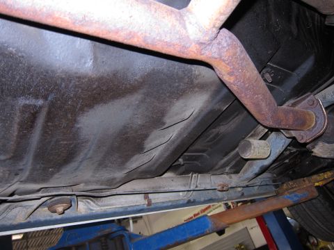 1991 Ford LTD Crown Victoria - The underbody of a vehicle, rusted exhaust pipes and a fuel tank, is visible in this close-up shot.