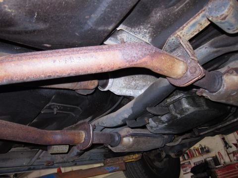 1991 Ford LTD Crown Victoria - Underside view of a vehicle's exhaust and drivetrain components, showing signs of wear and rust.