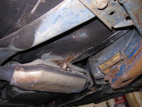 1991 Ford LTD Crown Victoria - The undercarriage of a vehicle, focusing on the exhaust pipe and suspension components, reveals signs of age and corrosion.