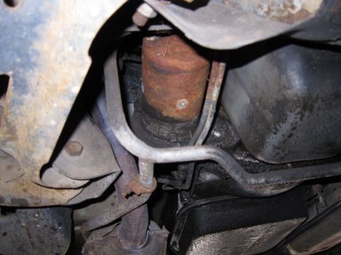 1991 Ford LTD Crown Victoria - Underside view of a vehicle's mechanical components, including a rusty canister and oil pan.