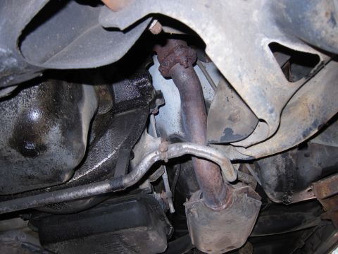 1991 Ford LTD Crown Victoria - Underside view of a vehicle's exhaust pipe and oil pan, showing components of the drivetrain.