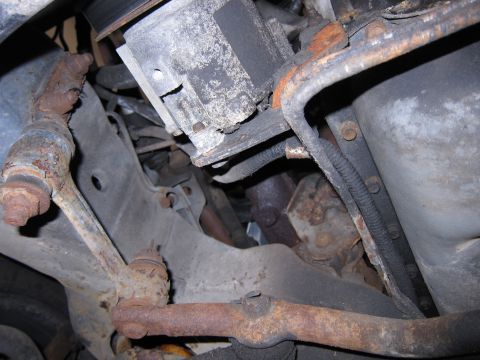 1991 Ford LTD Crown Victoria - Close-up of the rusty suspension and engine components underneath a vehicle.