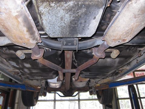 1991 Ford LTD Crown Victoria - The undercarriage of a vehicle is shown, highlighting the exhaust system and fuel tank components.