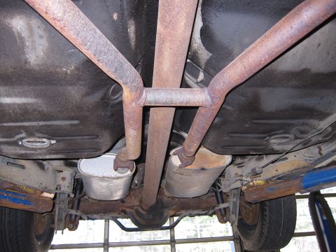 1991 Ford LTD Crown Victoria - The underside of a vehicle reveals a rusty exhaust system and suspension parts, with the car elevated on a lift.