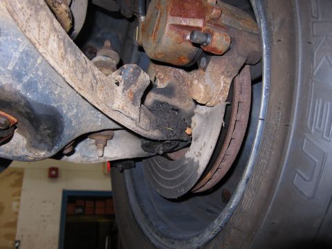 1991 Ford LTD Crown Victoria - Close-up view of a heavily rusted brake caliper and rotor assembly, likely from an older vehicle.
