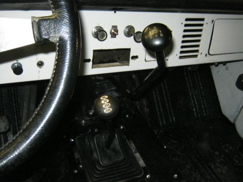 1970 Ford Bronco - Close-up of the dashboard and floor console, highlighting the manual transmission and transfer case shifters.