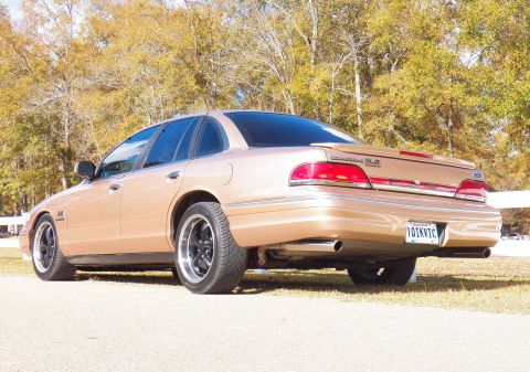 1993 Ford Crown Victoria - Rear view of a gold 1993 Ford Crown Victoria with aftermarket wheels parked outdoors.