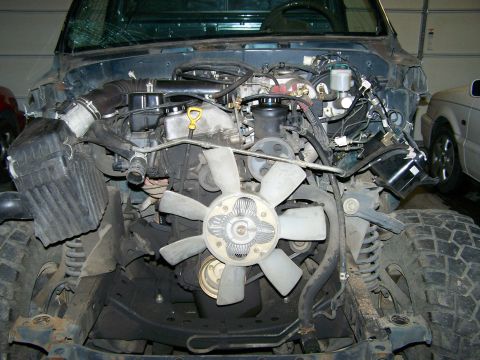 1988 Suzuki Samurai - The engine bay of a vehicle, a large fan and exposed tires. The registry information suggests a 1988 Suzuki Samurai, but the visual evidenc…