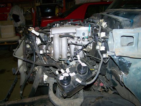 1988 Suzuki Samurai - Engine components are visible in this engine bay, with a red car in the background.