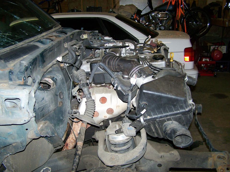 Engine bay with air intake and engine block visible, disassembled vehicle