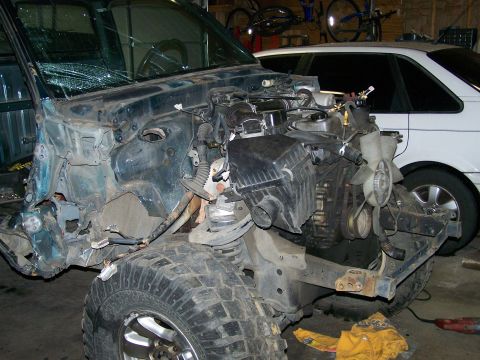 1988 Suzuki Samurai - Vehicle engine bay showing damage and exposed components, with another car visible behind.