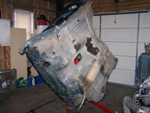1988 Suzuki Samurai - Car chassis is tilted on a stand in a garage setting.