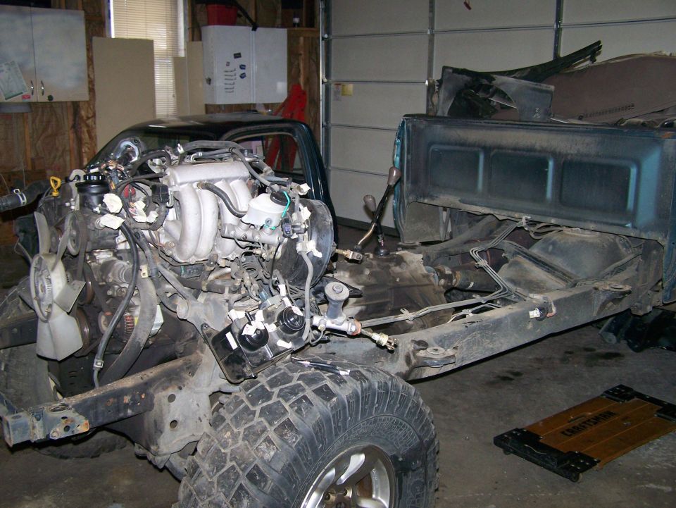 Engine bay of a truck with engine removed, showing chassis and transmission