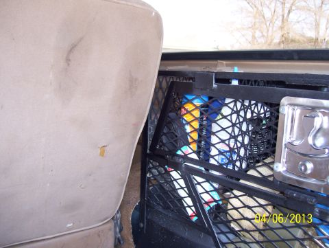 1990 Ford Bronco - Close-up of a black mesh cargo net and metal rack behind a tan seat back inside a vehicle cab; dated 04 06 2013.