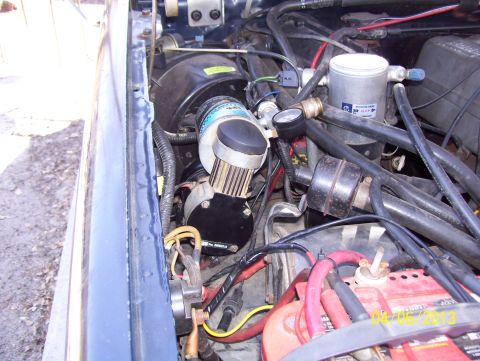 1990 Ford Bronco - Engine bay components including an air compressor, battery, and wiring are visible in this close-up shot.