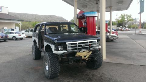 1994 Ford Bronco - This modified Ford Bronco is parked at a gas station with a mountainous landscape in the background.