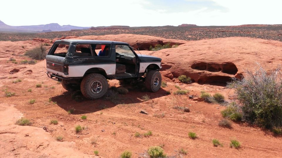 Black and white Ford Bronco off-road with doors open, parked on red rock terrain