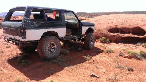 1994 Ford Bronco - This modified 1994 Ford Bronco is shown off-road in a desert landscape with its doors open.