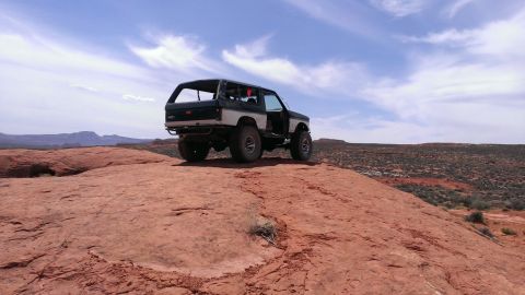 1994 Ford Bronco - A modified Ford Bronco sits on a rocky desert landscape under a partly cloudy sky.