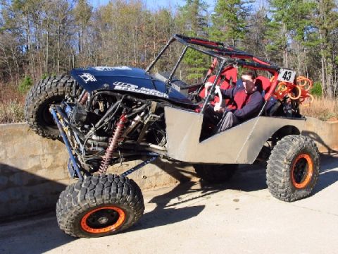 1994 Ford Bronco - Custom buggy with roll cage and large off-road tires is shown with two people inside.