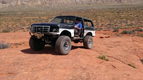 1994 Ford Bronco - A person sits in a modified Ford Bronco driving on a rocky, desert landscape.