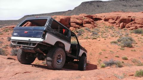 1994 Ford Bronco - Modified Ford Bronco navigates a challenging off-road course in a desert landscape.