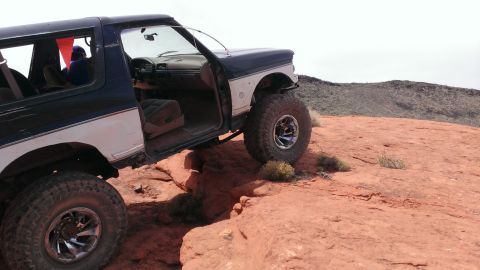 1994 Ford Bronco - A modified Ford Bronco navigates a challenging off-road course with its doors open.