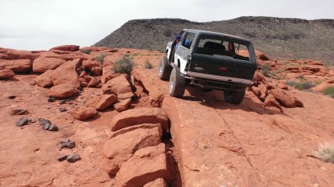1994 Ford Bronco - A Ford Bronco navigates a rocky off-road trail in a desert landscape.